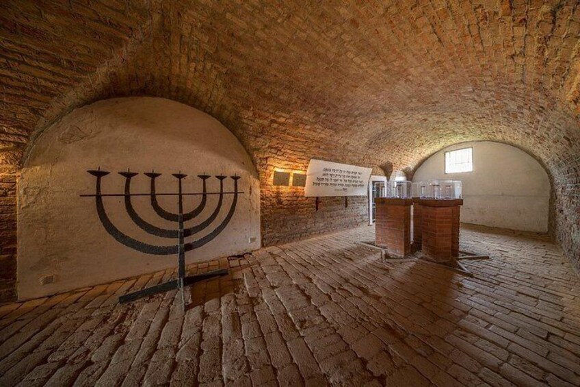 A room with a large menorah, brick walls, and a stone floor. 5