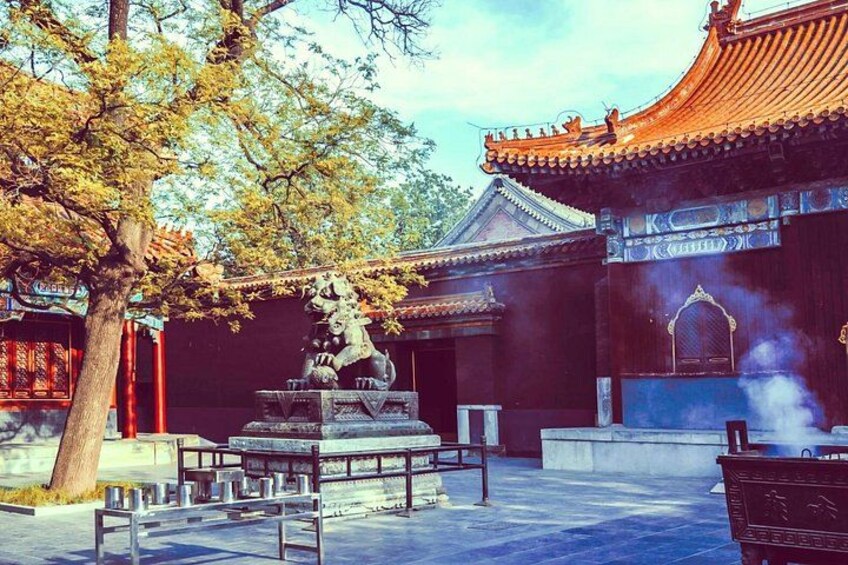 Un bâtiment traditionnel chinois, avec un toit recouvert de tuiles, une statue de pierre et un arbre au premier plan. 2
