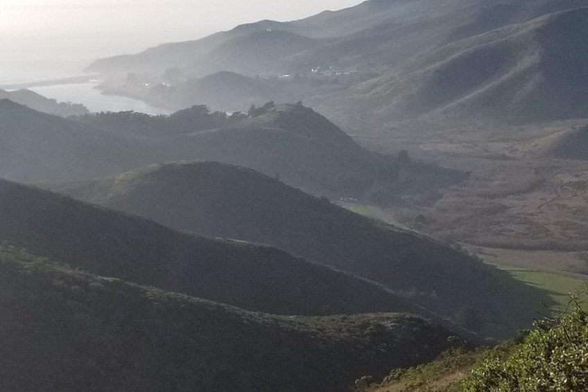 Rolling hills, a valley, and a distant body of water. 4
