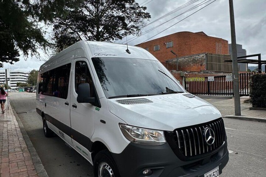 A white van parked on a street with a brick sidewalk and a building in the background. 2