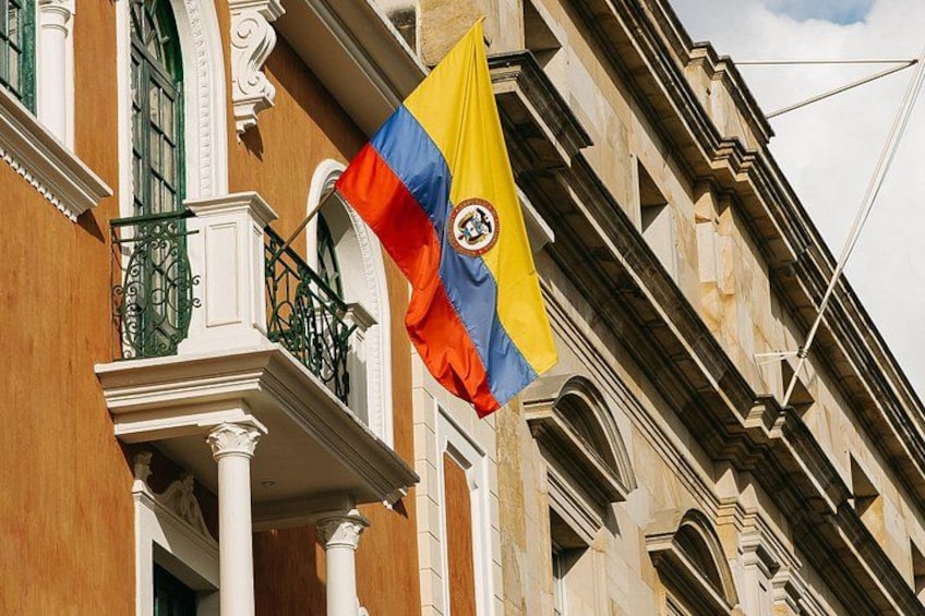 Eine Flagge mit gelb-blauer-roter Gestaltung, befestigt an einem Balkon eines Gebäudes mit aufwendiger Architektur. 3