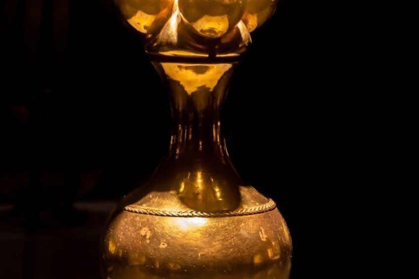 A golden vase with a textured surface and a braided cord. 4