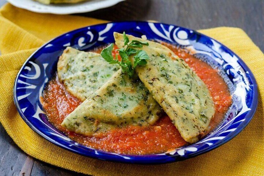 A plate of stuffed zucchini slices with a red sauce, garnished with herbs, on a blue and white patterned plate. 4