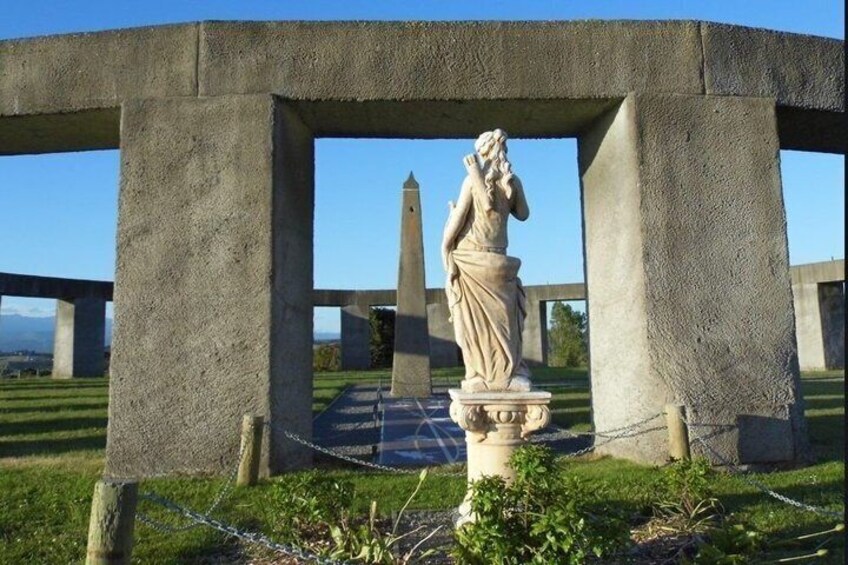 A statue in a concrete structure with a chain fence in a grassy area. 3