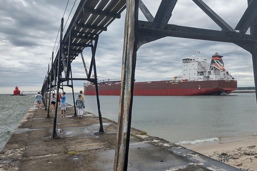 A large red cargo ship docked at a pier with a metal structure overhead. 2