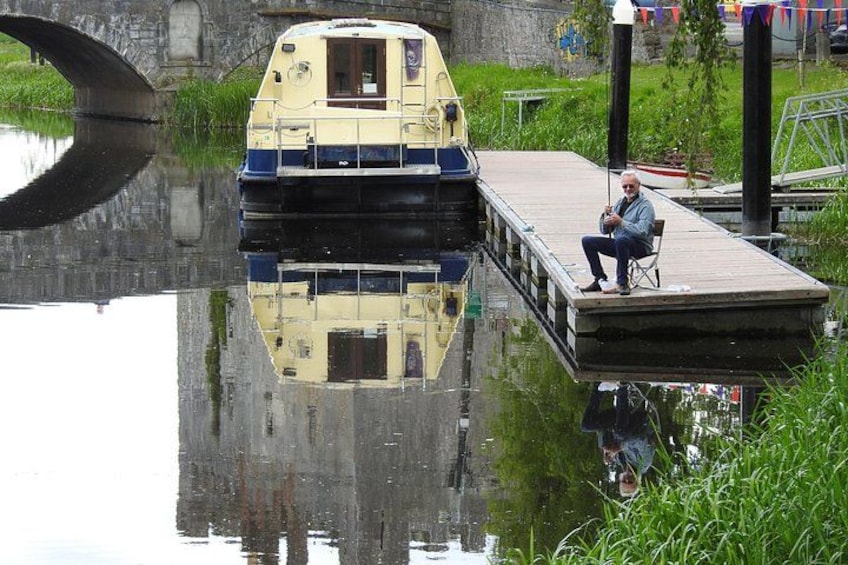 A boat docked at a pier with a man sitting on a chair. 2
