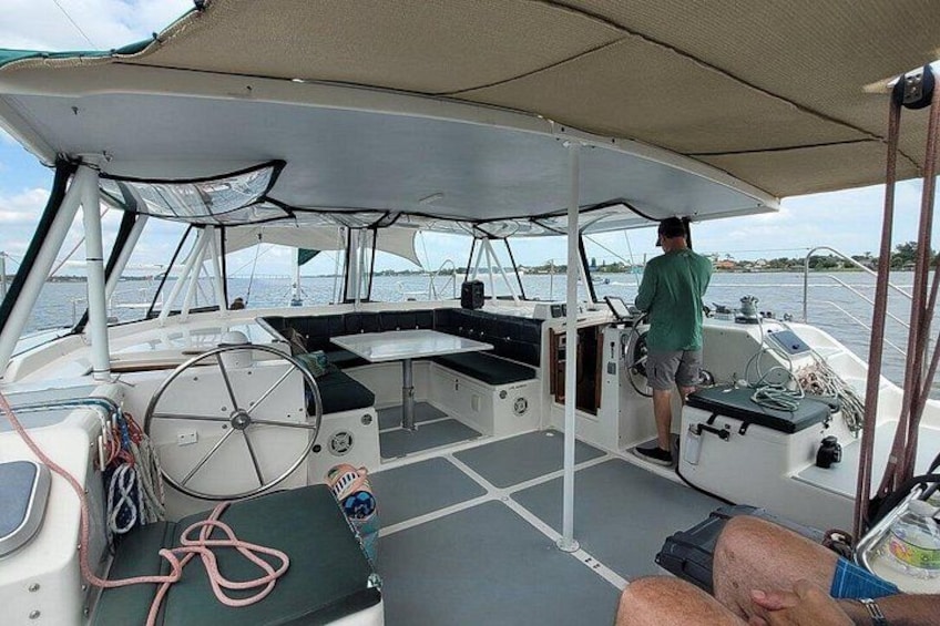 A boat's deck with a person standing at the helm, a steering wheel, and a canopy overhead. 5