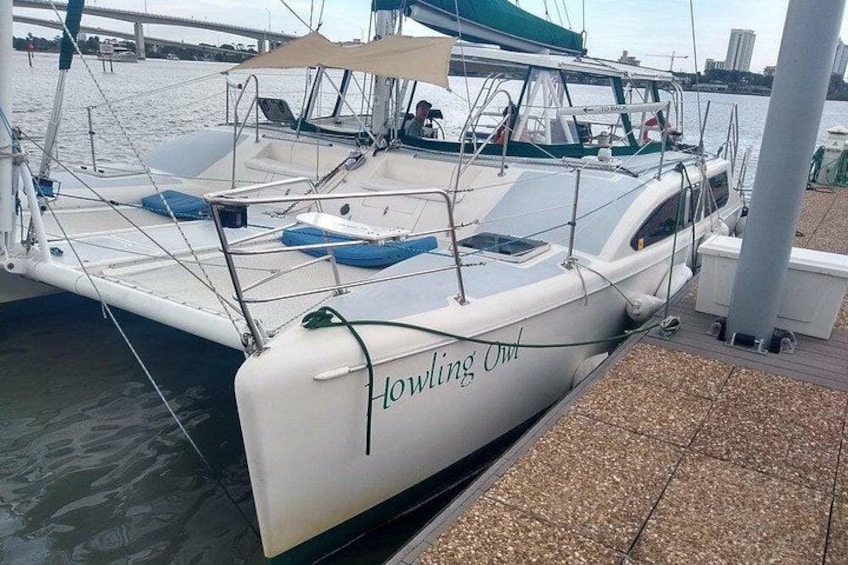 A white boat named 'Howling Owl' docked at a marina with a covered area and a waterway in the background. 3