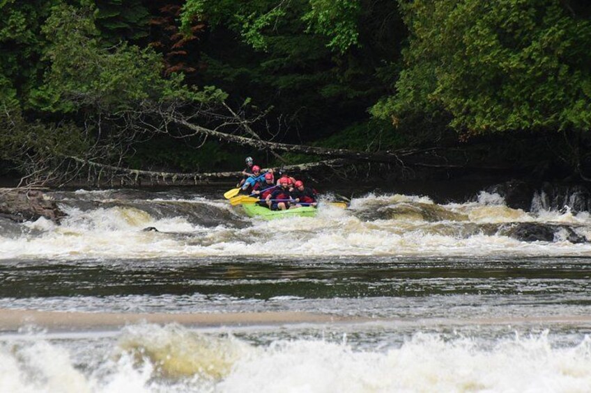 Un groupe de personnes fait du rafting sur une rivière, entourée d’un paysage rocheux et d’une végétation luxuriante. 5