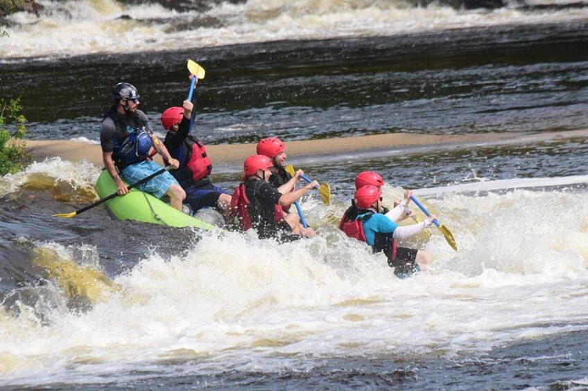 Un groupe de personnes à bord d’un kayak vert qui navigue dans des rapides. 3