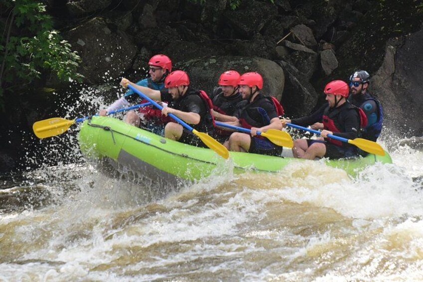 Un groupe de personnes à bord d’un radeau gonflable vert naviguant sur une rivière. 2