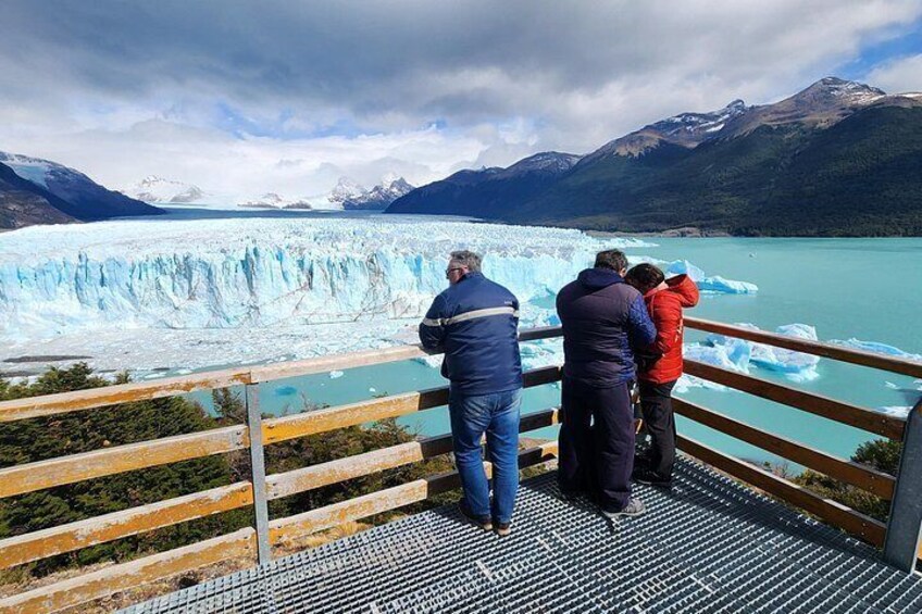 A glacier with people observing from a wooden viewing platform. 1
