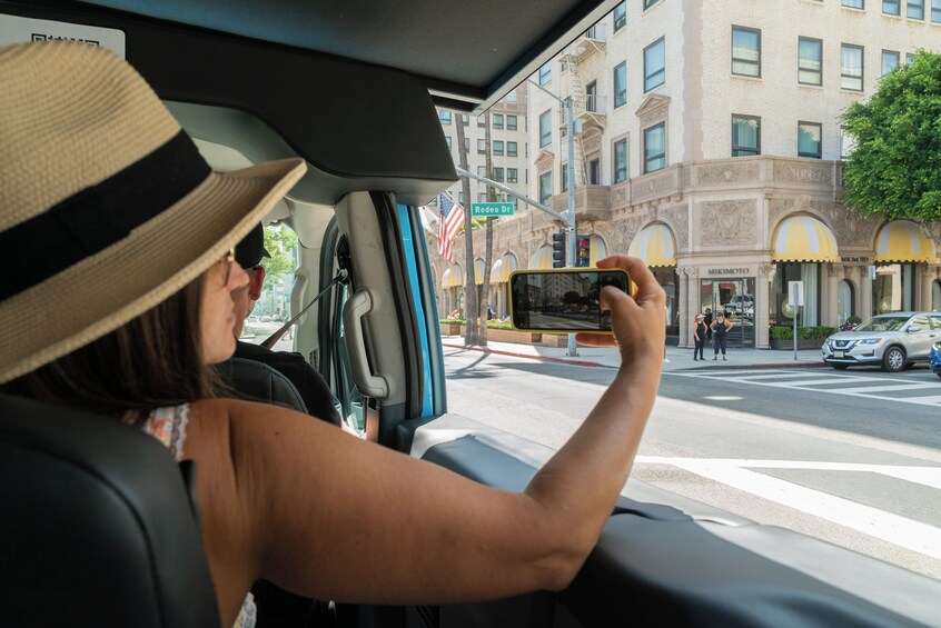 A person taking a photo of a street scene from inside a vehicle. 2