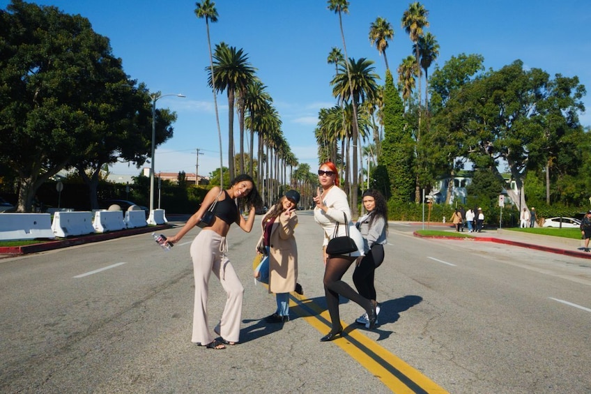 A group of people posing on a street lined with palm trees. 4