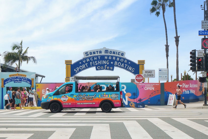 A colorful bus with people on it, a road closure sign, and a sign for Santa Monica Yacht Harbor. 1