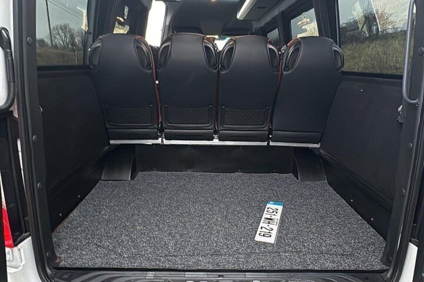 The interior of a vehicle with a black carpeted floor and three black seats. 2
