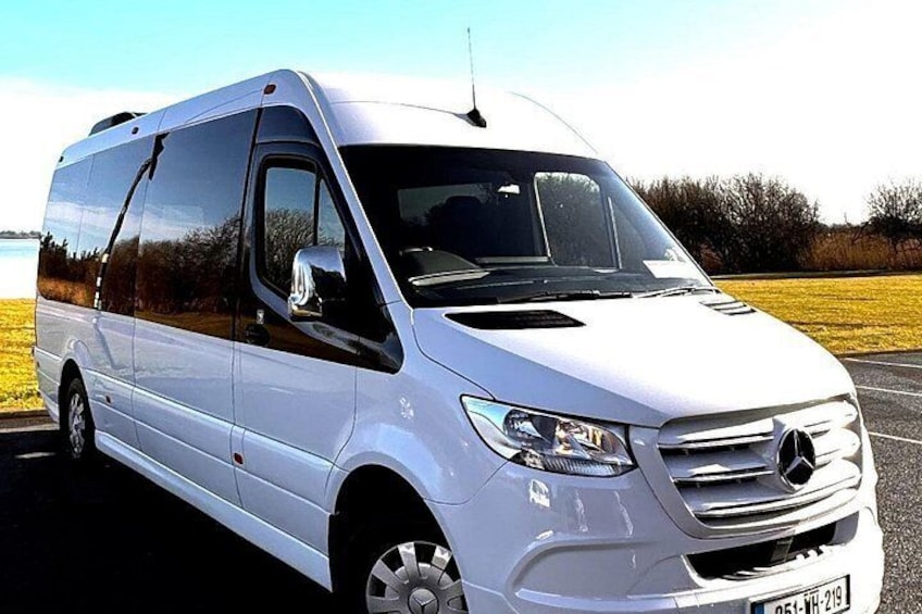 A white Mercedes-Benz Sprinter van parked on a road with a clear sky and a field in the background. 4