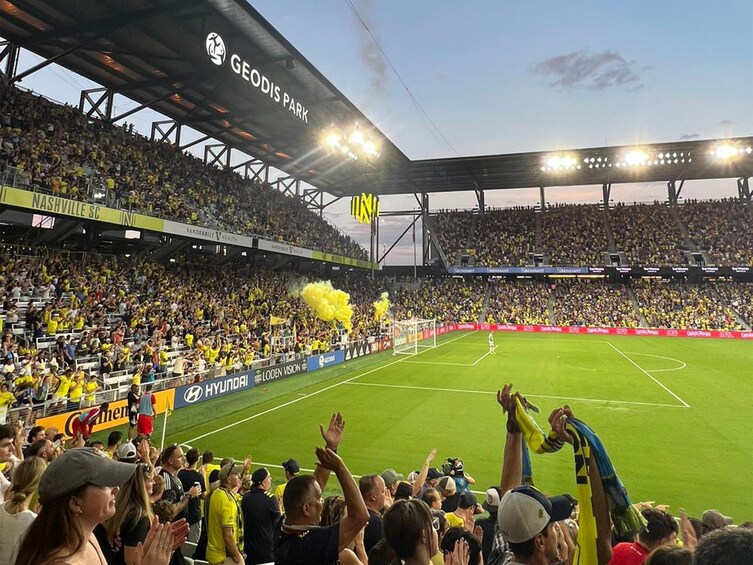 Katsomoiden täyttämä stadion, jalkapallokenttä ja suuri katos, jonka päälle on kirjoitettu teksti ”GEODIS PARK”. 1