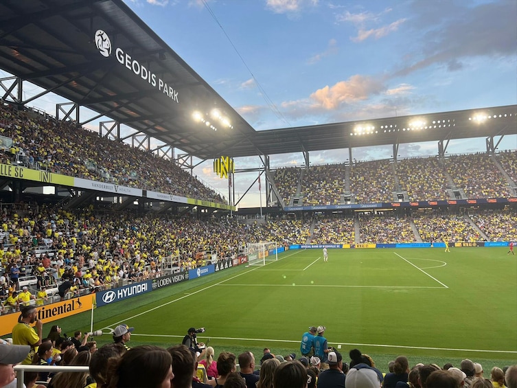 Jalkapallostadion, joka on täynnä katsojia, jalkapallokenttä ja mainosbanderollit. 4