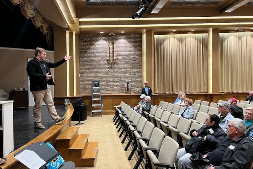 A person presenting in a lecture hall with an audience seated. 5