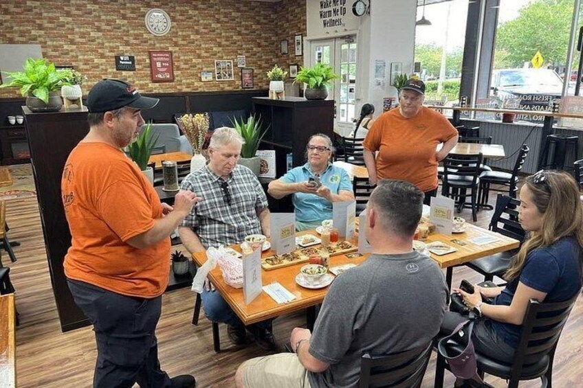 A group of people seated at a restaurant table with food and drinks. 3