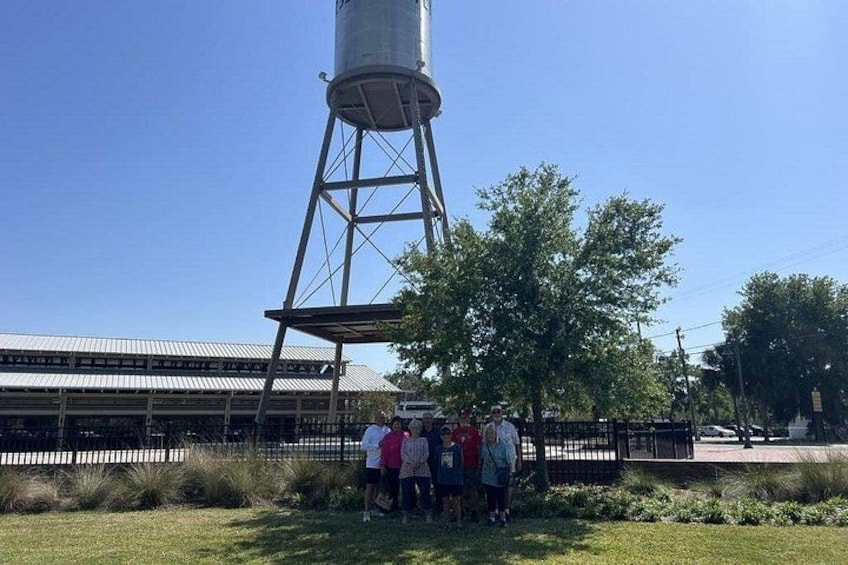 A water tower, a group of people, and a building with a metal roof. 3