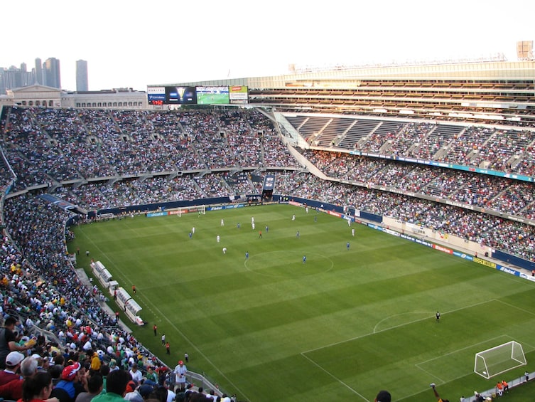 Ein großes Stadion voller Zuschauer, ein Fußballfeld und eine Anzeigetafel. 1