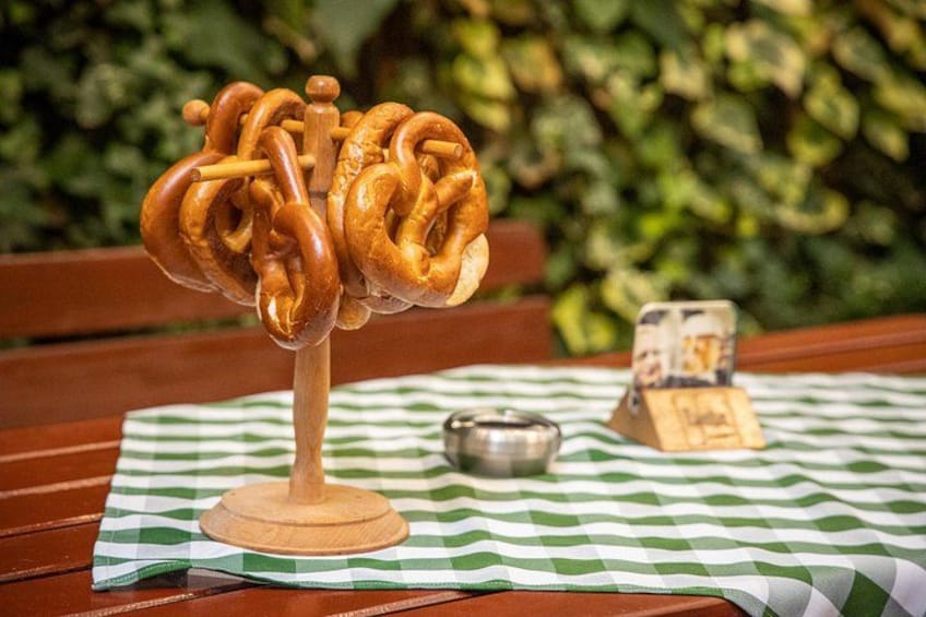 A pretzel on a wooden stand on a checkered tablecloth. 4