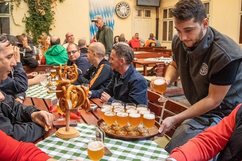A group of people sitting at a table with beer glasses and pretzel stands. 1