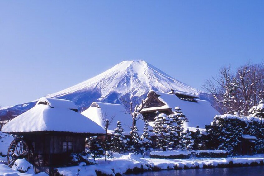 A snow-covered mountain, traditional buildings, and a wooden water wheel. 2