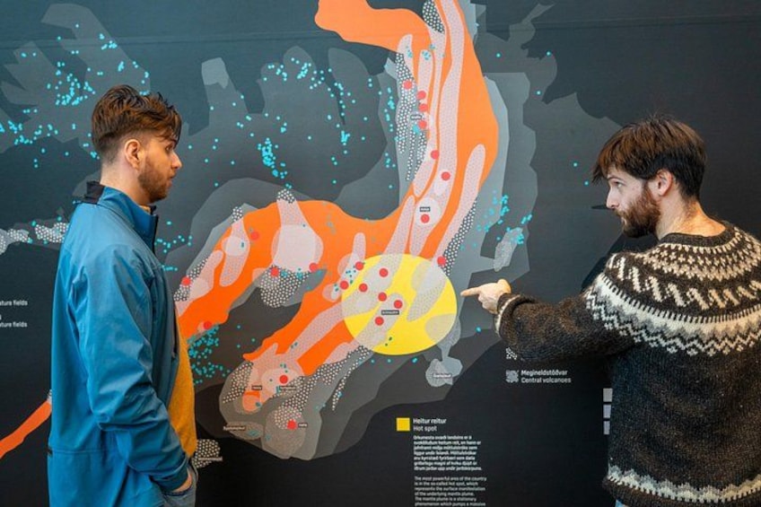 Two people examining a large, colorful, abstract map with various shapes and dots. 2