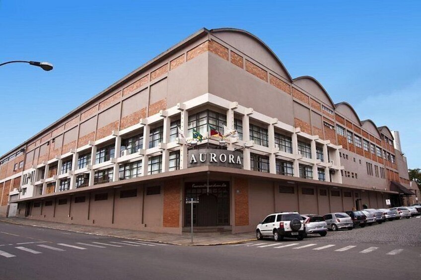 A large building with the name 'AURORA' on the facade, multiple windows, and parked cars along the street. 5