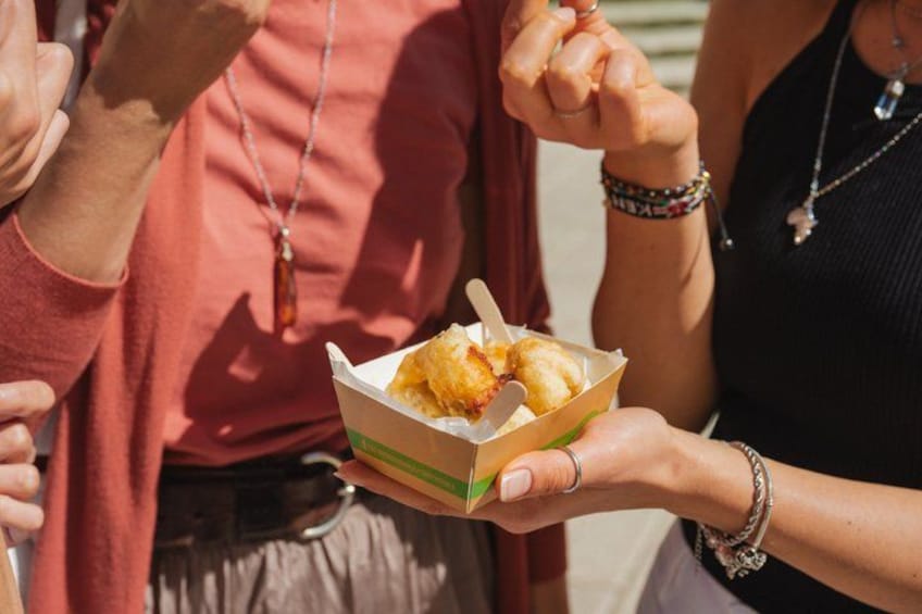 A person holding a box of fried food. 4