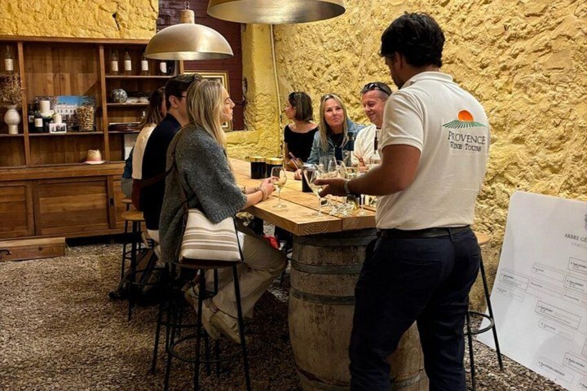 A group of people at a bar with a rustic stone wall background, wooden shelves, and hanging pendant lights. 2