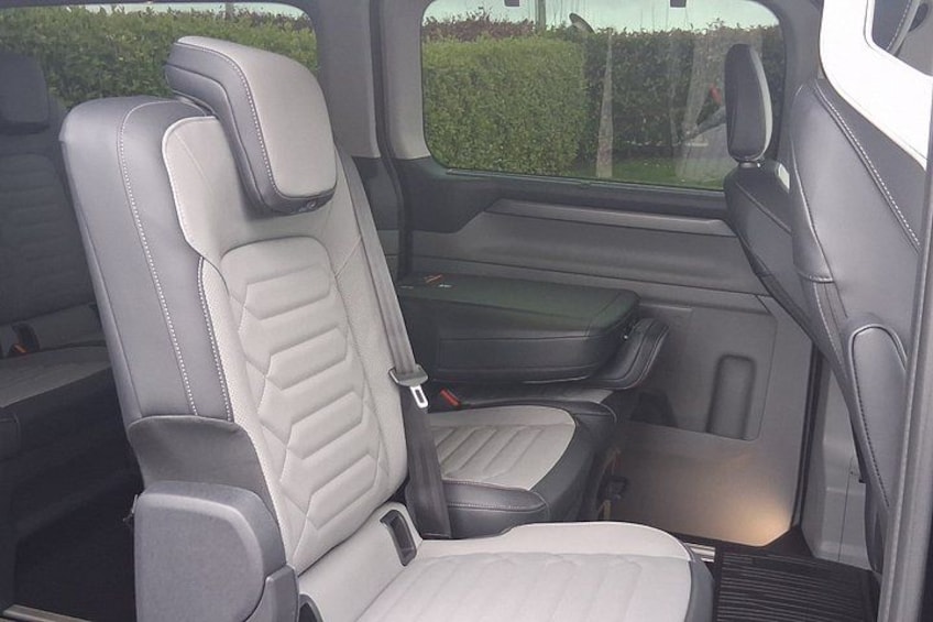 Interior de vehículo con asientos de cuero gris y blanco, una consola central y un espejo retrovisor. 2