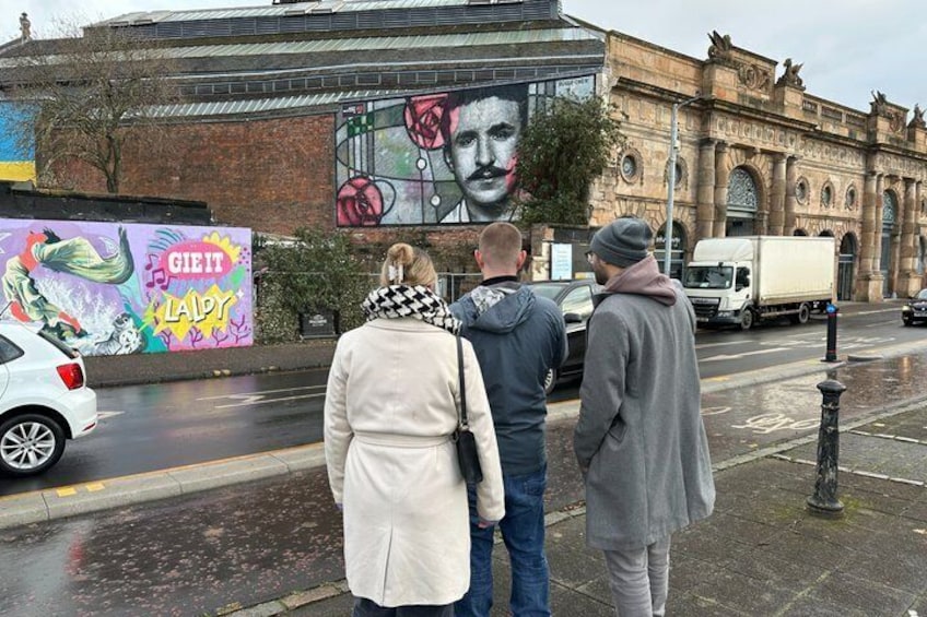 A mural on a building, a wet street, and a truck. 5