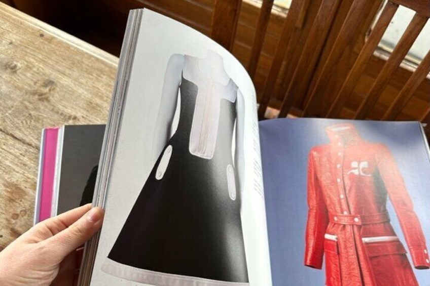 A person holding a magazine with a dress and a red jacket on the cover. 2