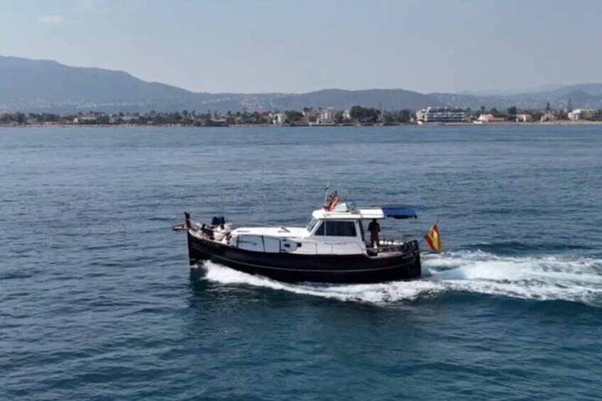 A boat on a calm body of water with a distant shoreline and mountains in the background. 4
