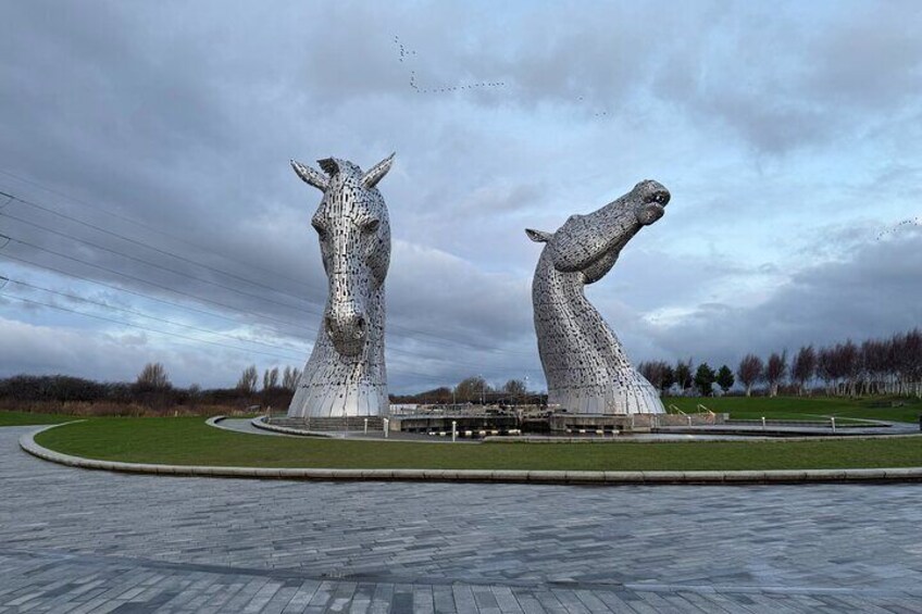 The Kelpies, two large horse sculptures, in a landscaped area with a paved walkway. 2