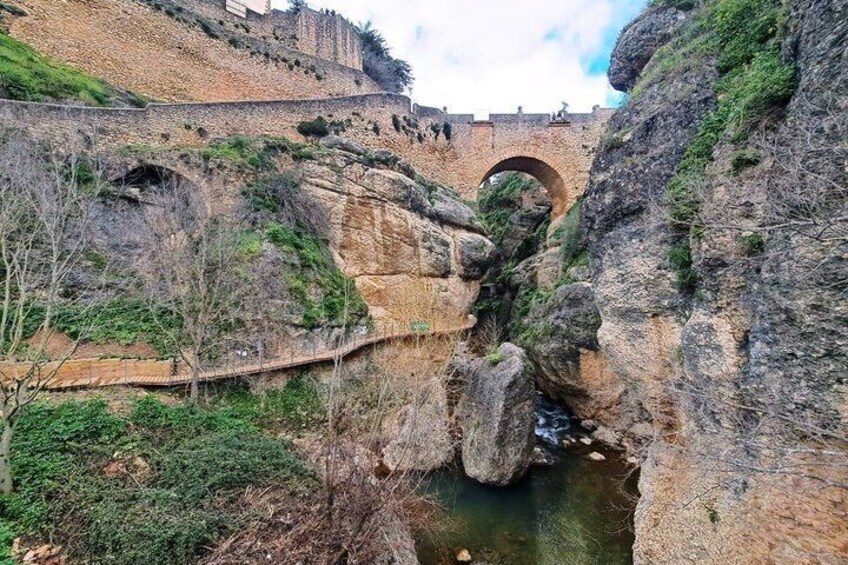 A stone bridge over a river, surrounded by rocky terrain and greenery. 5