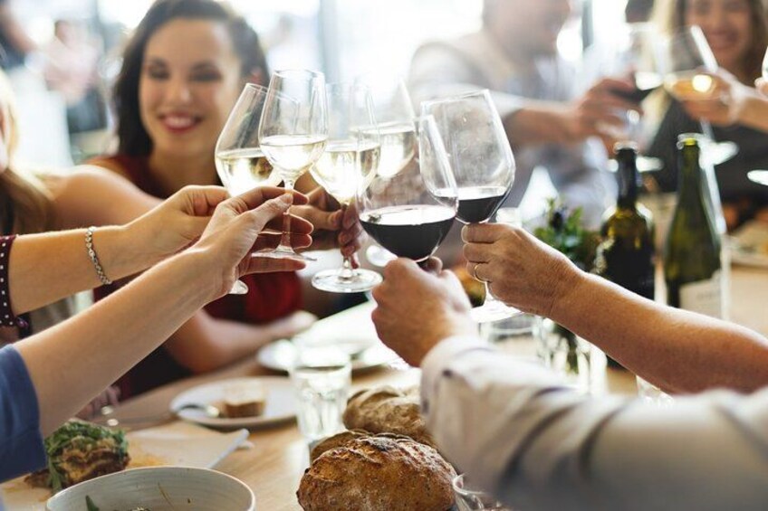 Mensen die met wijnkansen proosten, een brood en een fles wijn op een tafel. 3