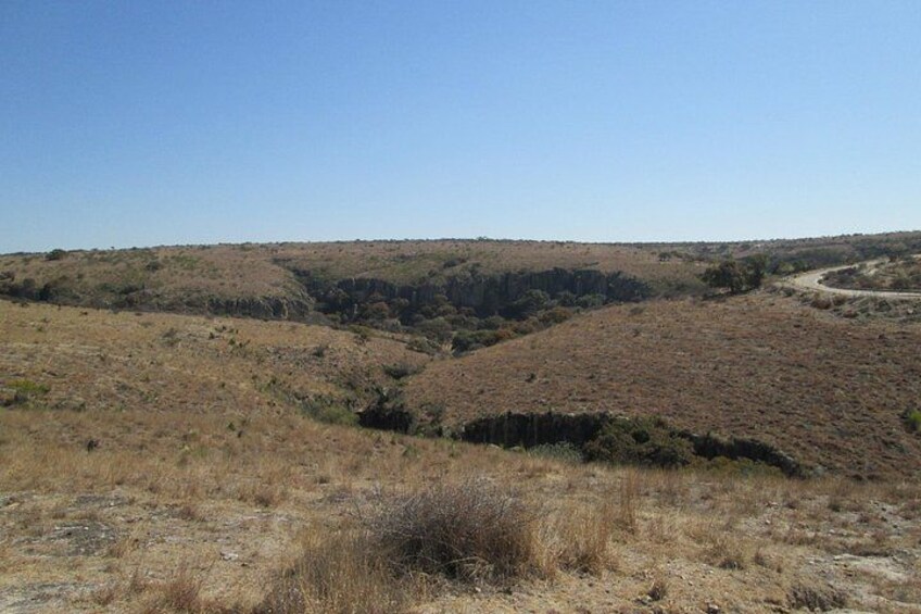 Un paisaje árido y montañoso con vegetación escasa y un camino sinuoso. 5