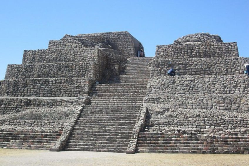 Una gran pirámide de piedra con varios niveles y una escalera que conduce a la cima. 1