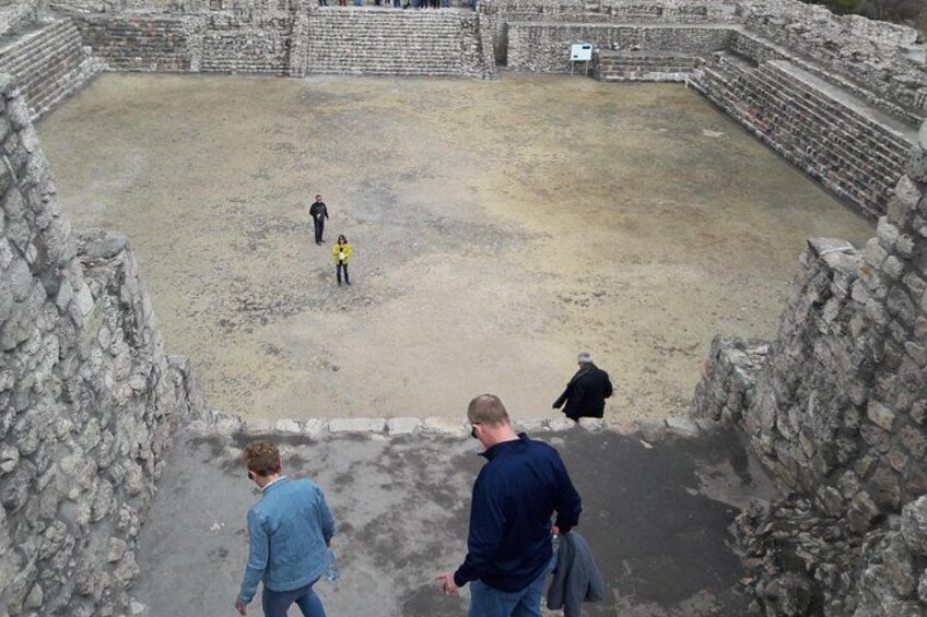 Un antiguo anfiteatro de piedra con un espacio abierto central y asientos escalonados. 2