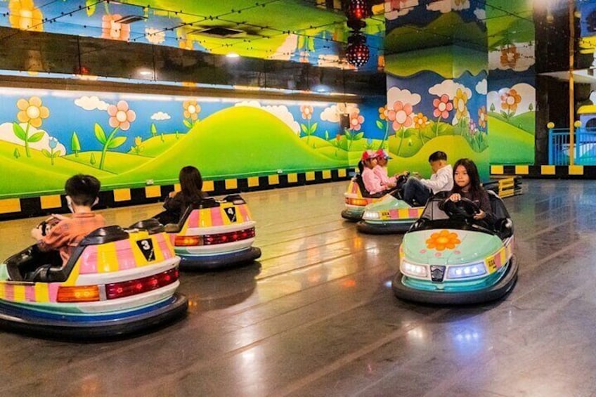 Children riding bumper cars in an indoor amusement area with colorful murals. 1