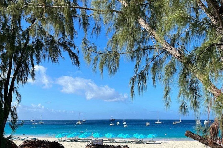 A beach with clear blue water, boats, and umbrellas. 5