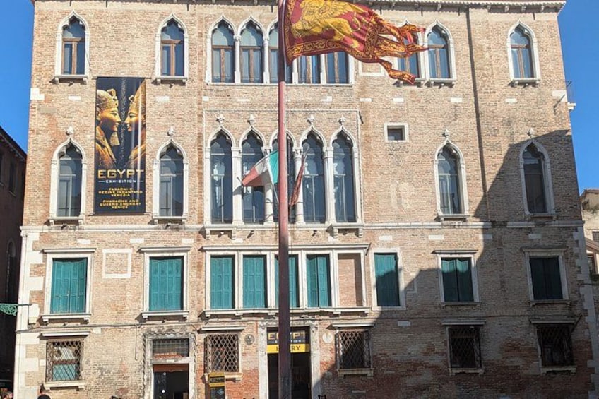 Un edificio histórico con ventanales arqueados y un gran cartel con motivos egipcios. 2