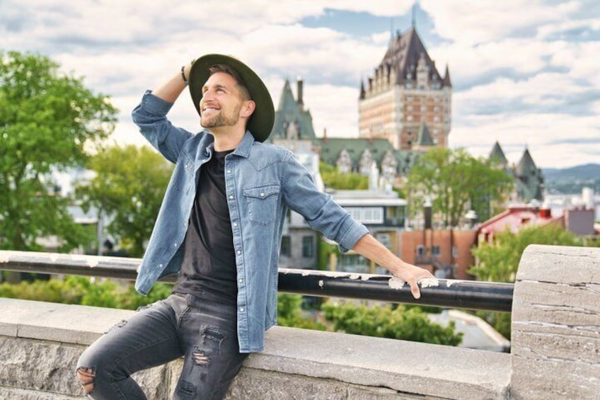 A person sitting on a stone ledge with a cityscape in the background. 1