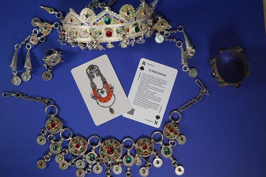 Una colección de joyería que incluye una corona, aretes y un collar con piedras preciosas, junto con una tarjeta y un documento. 2