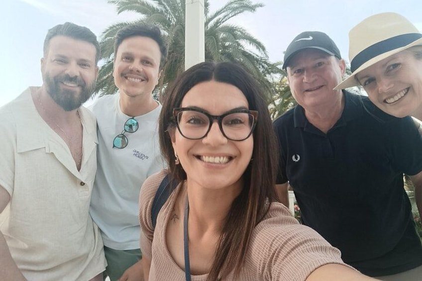 A group of people outdoors with palm trees in the background. 1
